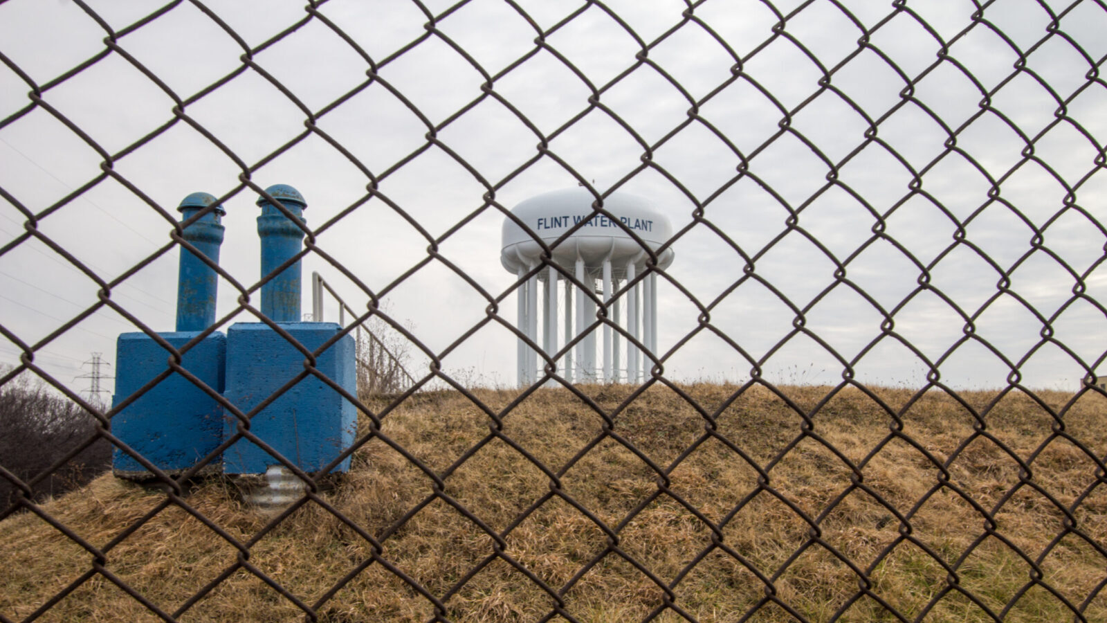 Water tower of Flint Michigan through a chain linked fence Water tower of Flint Michigan through a chain linked fence