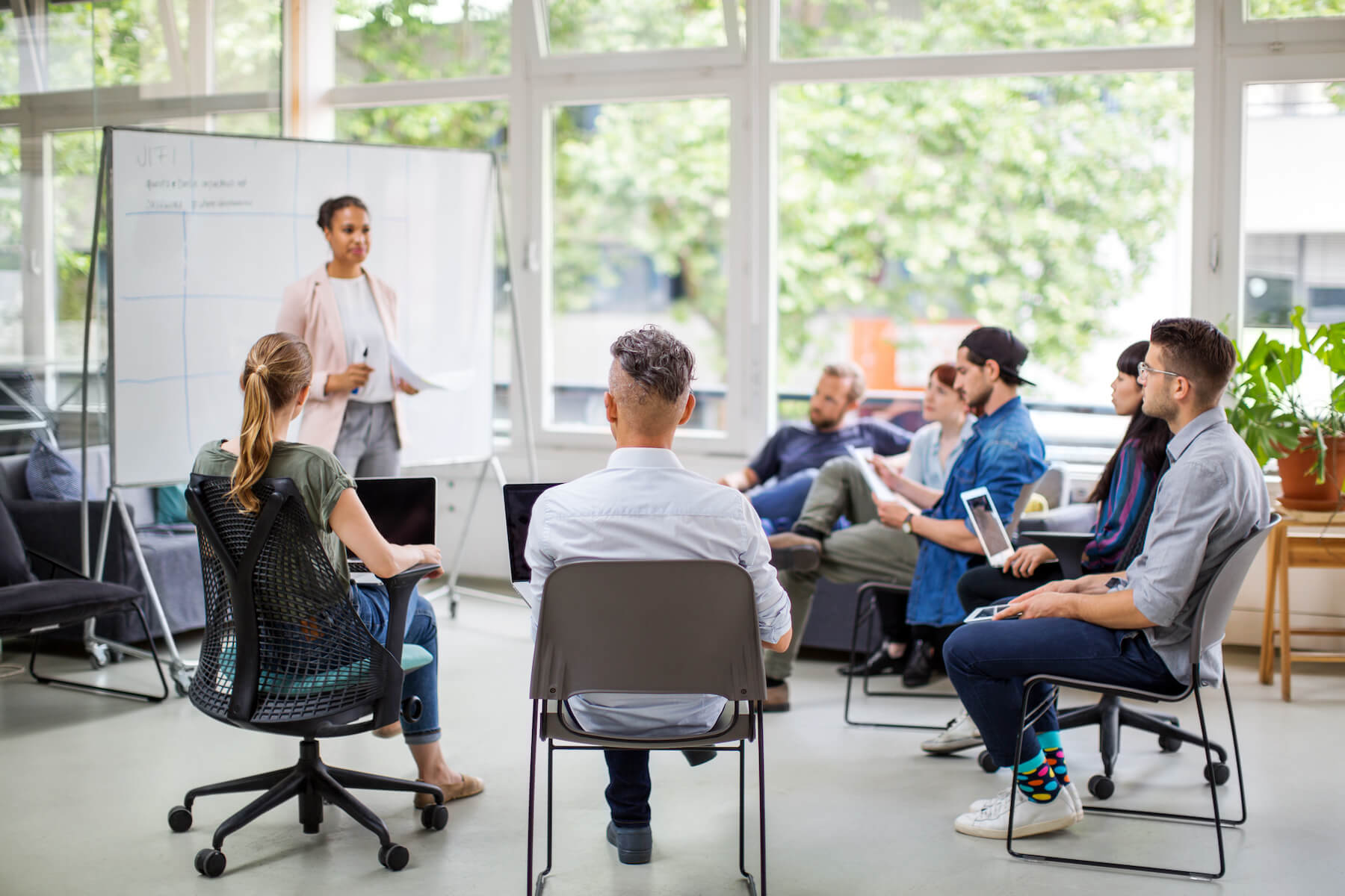 An instructor standing at a whiteboard addressing a small circle of seated students An instructor standing at a whiteboard addressing a small circle of seated students